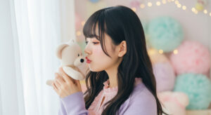 Young woman in a lavender sweater kisses a white plush bear by a window with soft pastel decor.