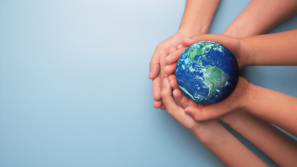 Hands cradle a small globe of Earth against a light blue background, symbolizing care for the planet.